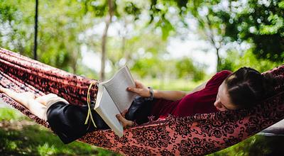 Girl reading a book relaxing in a hammock